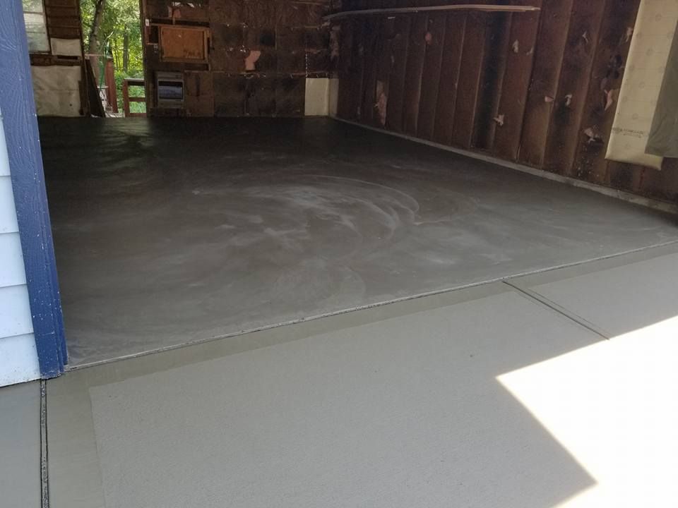 a concrete floor in a garage with a wooden wall .