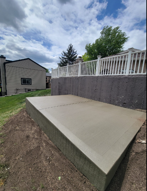 a large concrete slab is sitting in front of a house with a white railing .