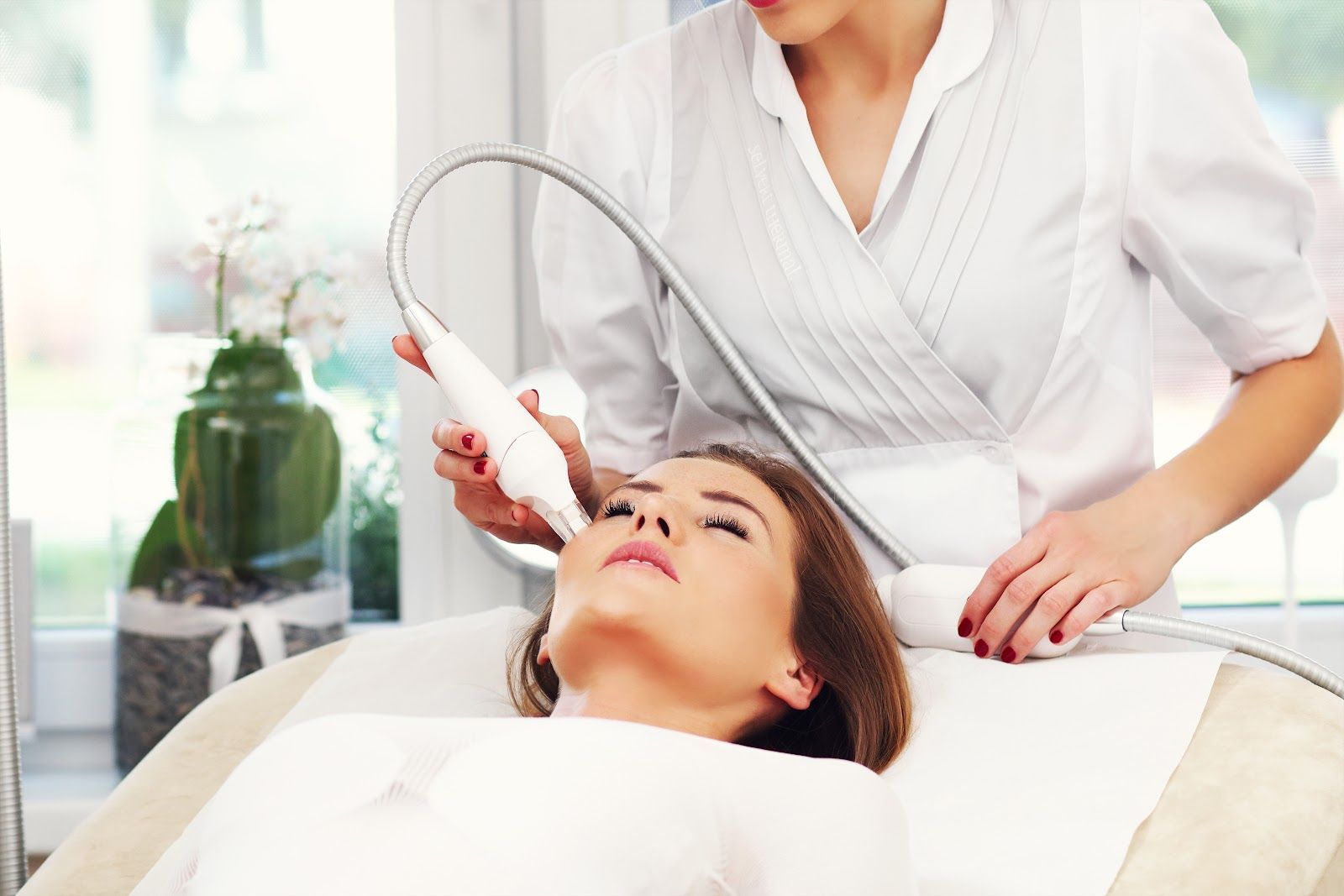 Woman receiving facial treatment with a handheld device in a spa setting