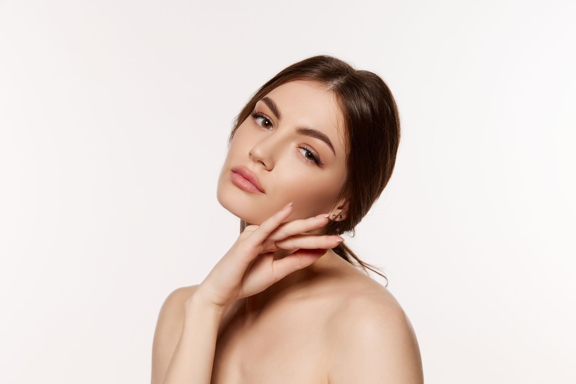 Portrait of a person with dark hair posing against a white background, hand resting on chin
