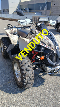 ATV mimetico parcheggiato sull'asfalto, vicino agli edifici.