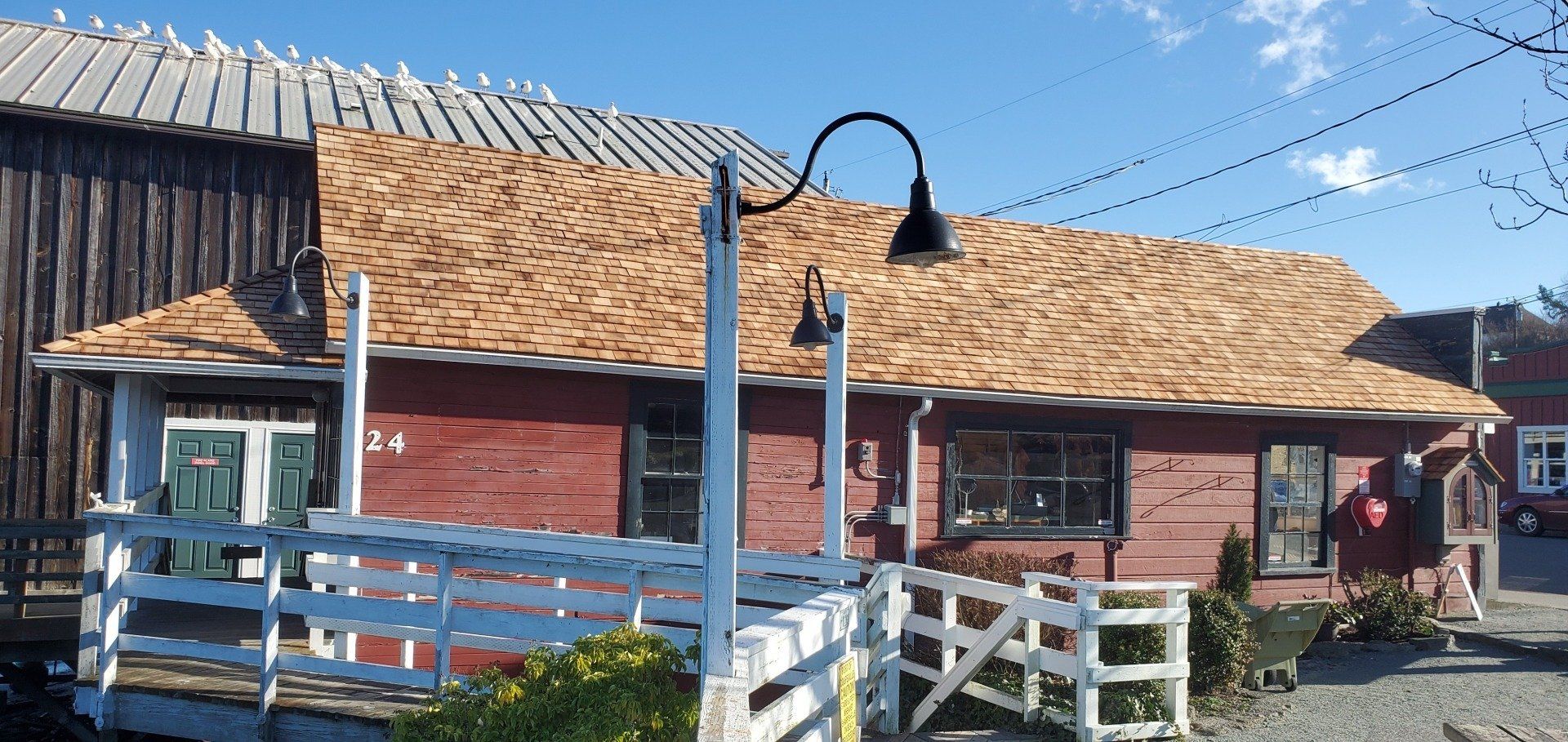 A red building with a wooden roof and a white fence in front of it.