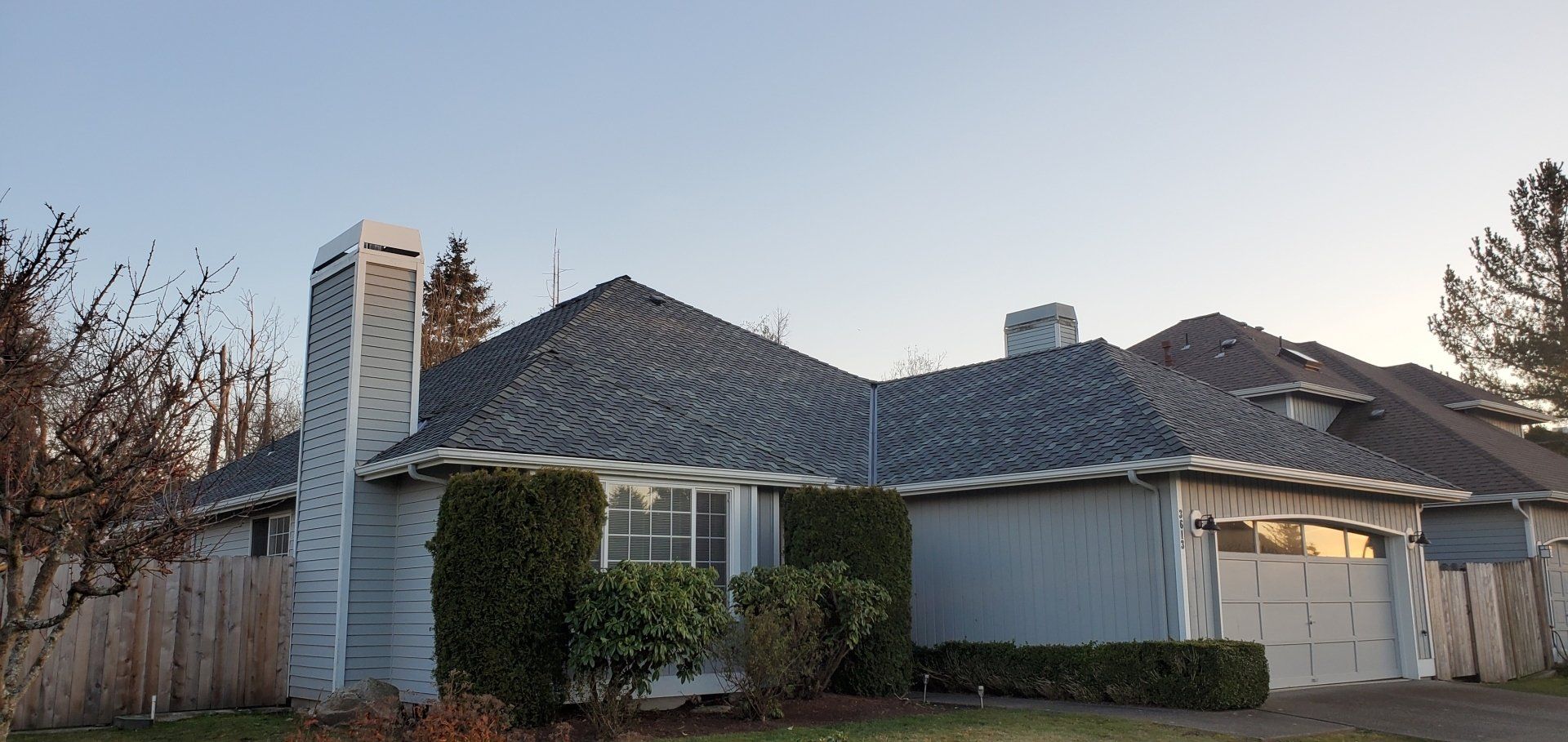 A house with a gray roof and a white garage door