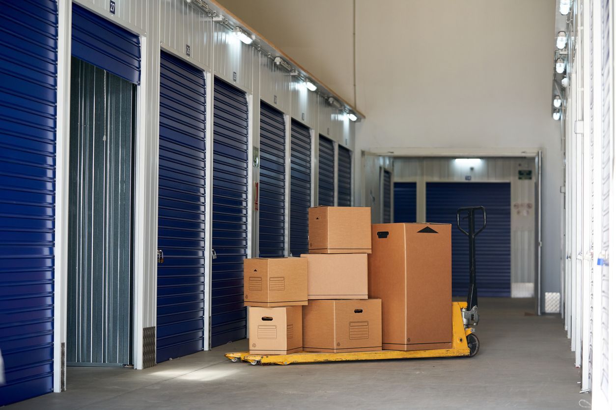 Cardboard moving boxes stacked on a pallet jack in the hallway of an indoor self storage facility wi
