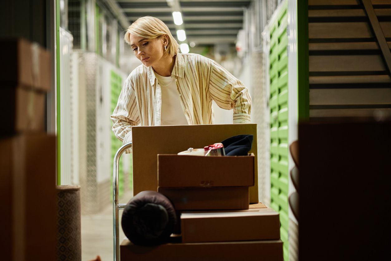 Women pushing a dolly into a storage unit that's already full.