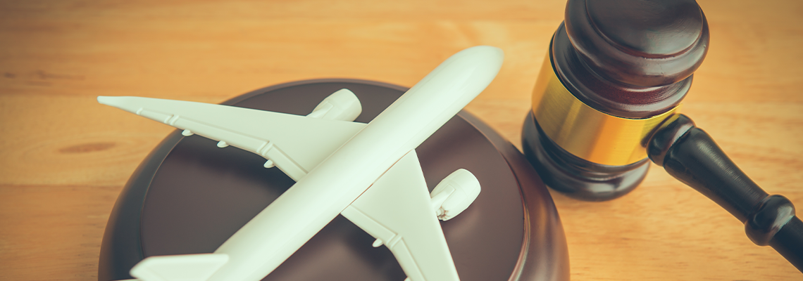 White airplane model on a brown suitcase with a judge’s gavel, suggesting travel law or airline regulation