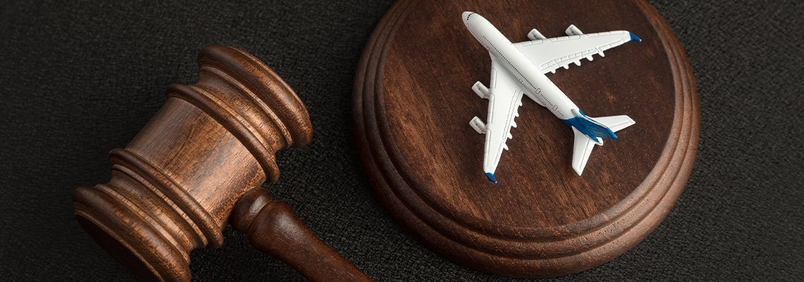 Wooden judge’s gavel beside a small white toy airplane on a round wooden base