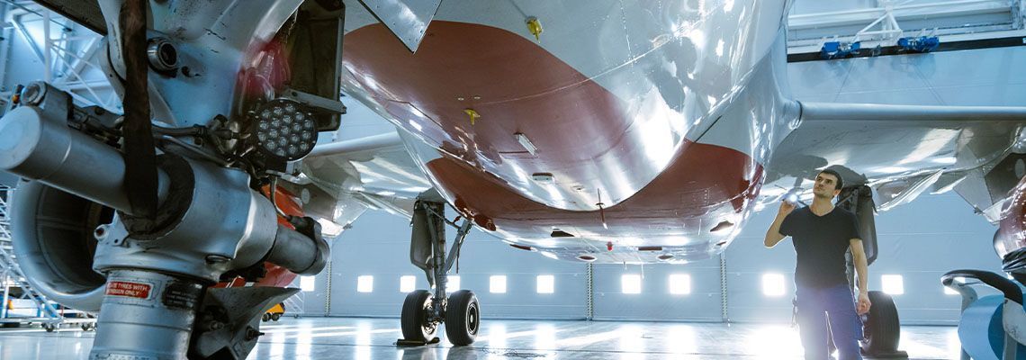 Robotic spacecraft in a hangar with astronauts inspecting it under bright lights