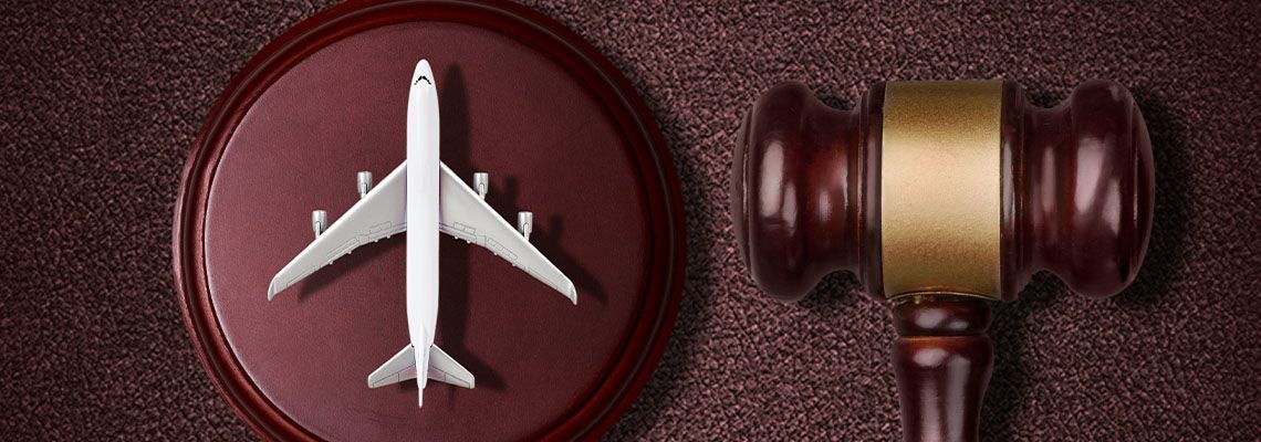 White airplane model and judge’s gavel on a burgundy surface, symbolizing travel law or regulation