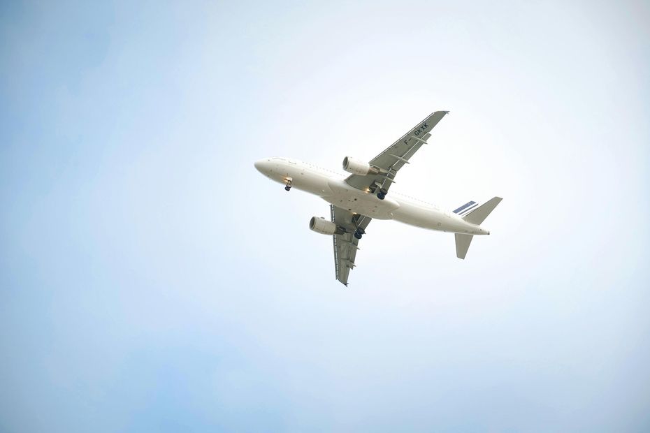 Commercial airplane flying overhead against a pale sky