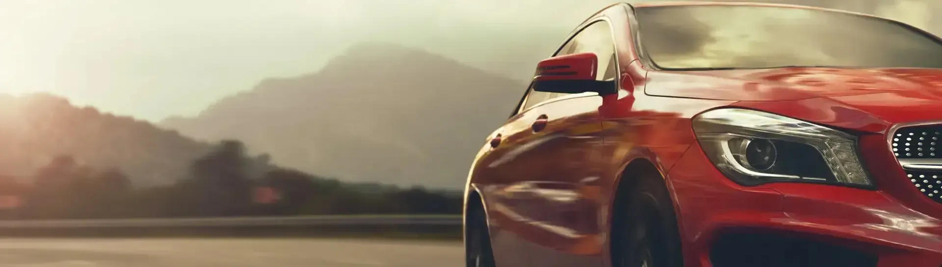 Red sports car driving on a road with mountains in the background
