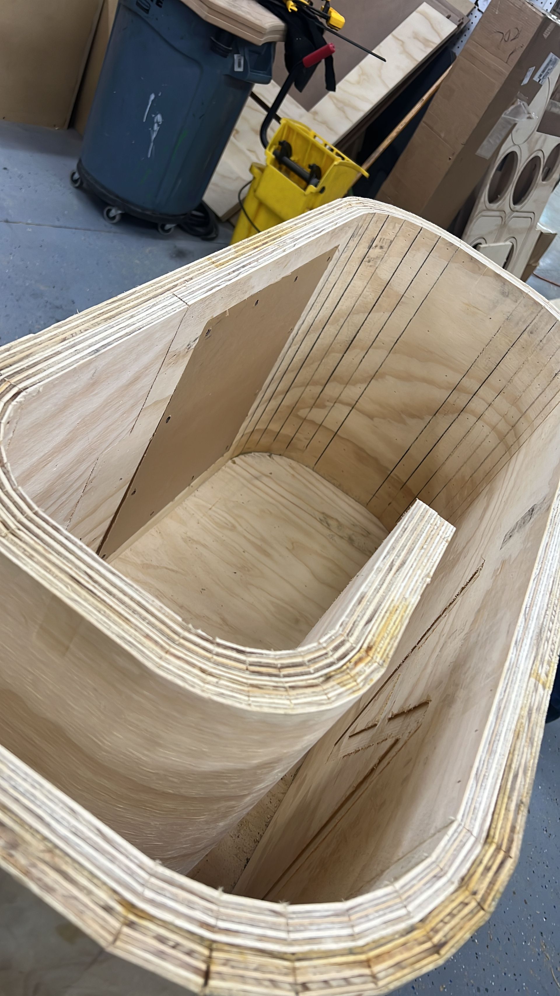 A large piece of wood is sitting on the floor next to a trash can.