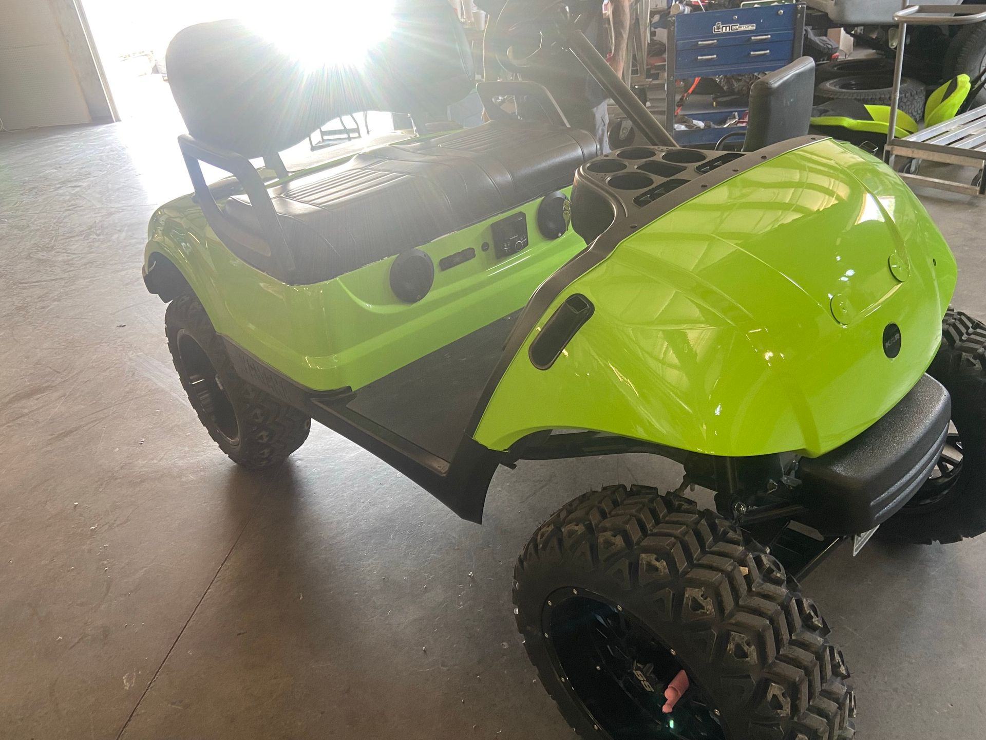 A neon green golf cart is parked in a garage.