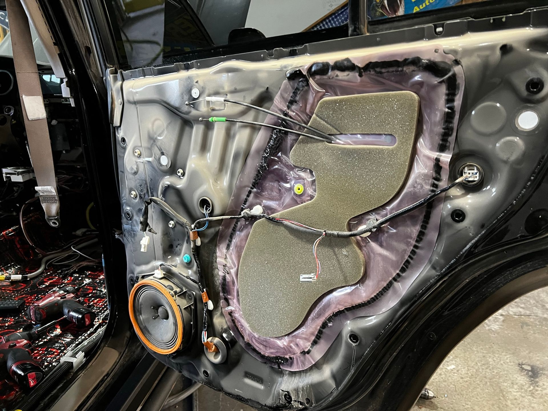 The rear door of a car is being installed with speakers.