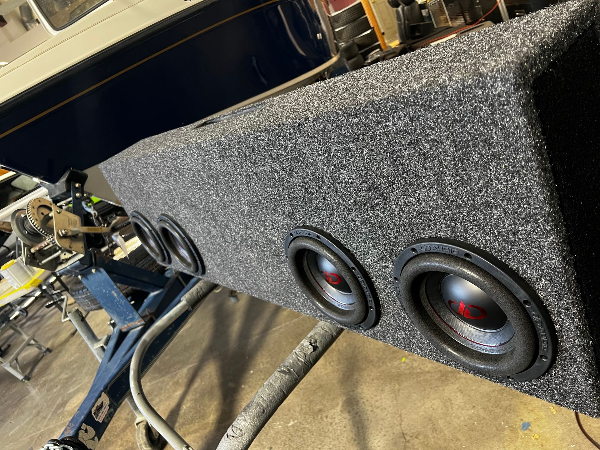A subwoofer box is sitting on the ground next to a boat.