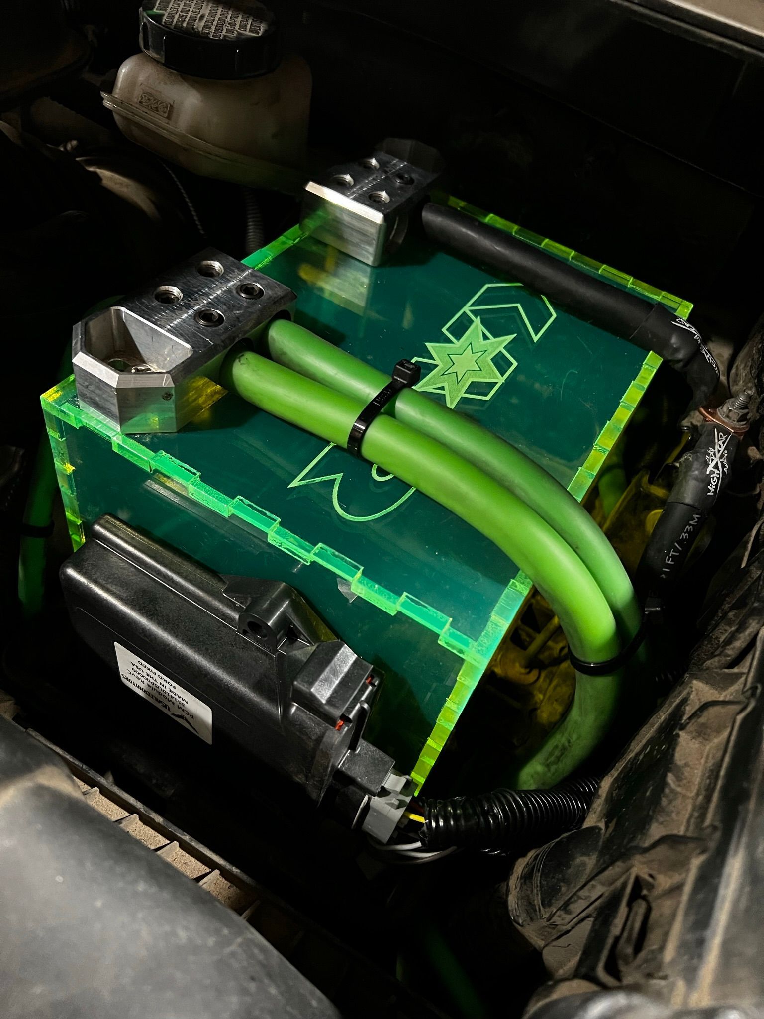 A green box with green hose attached to it is in the trunk of a car.