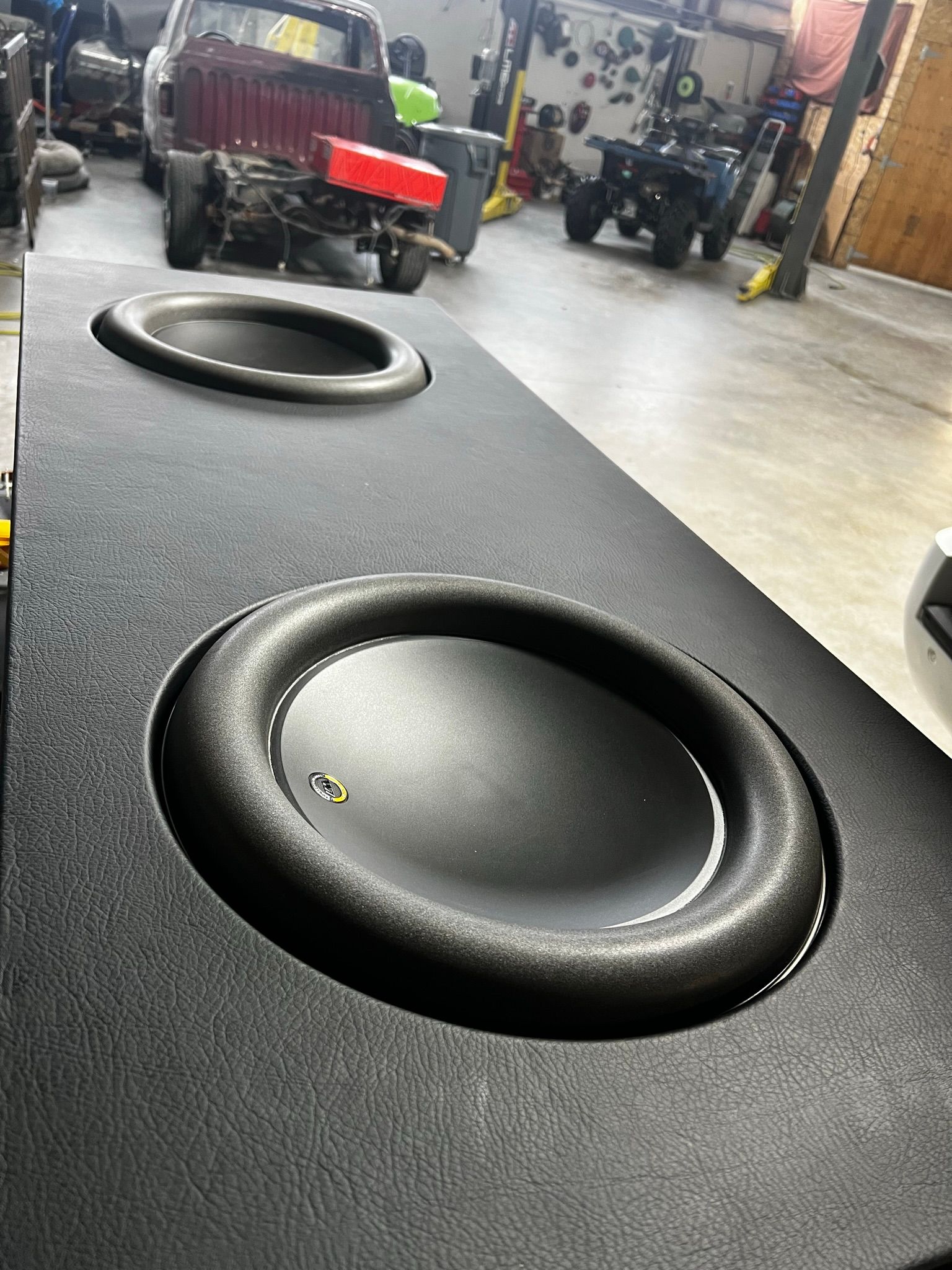 A black subwoofer is sitting in a garage next to a truck.