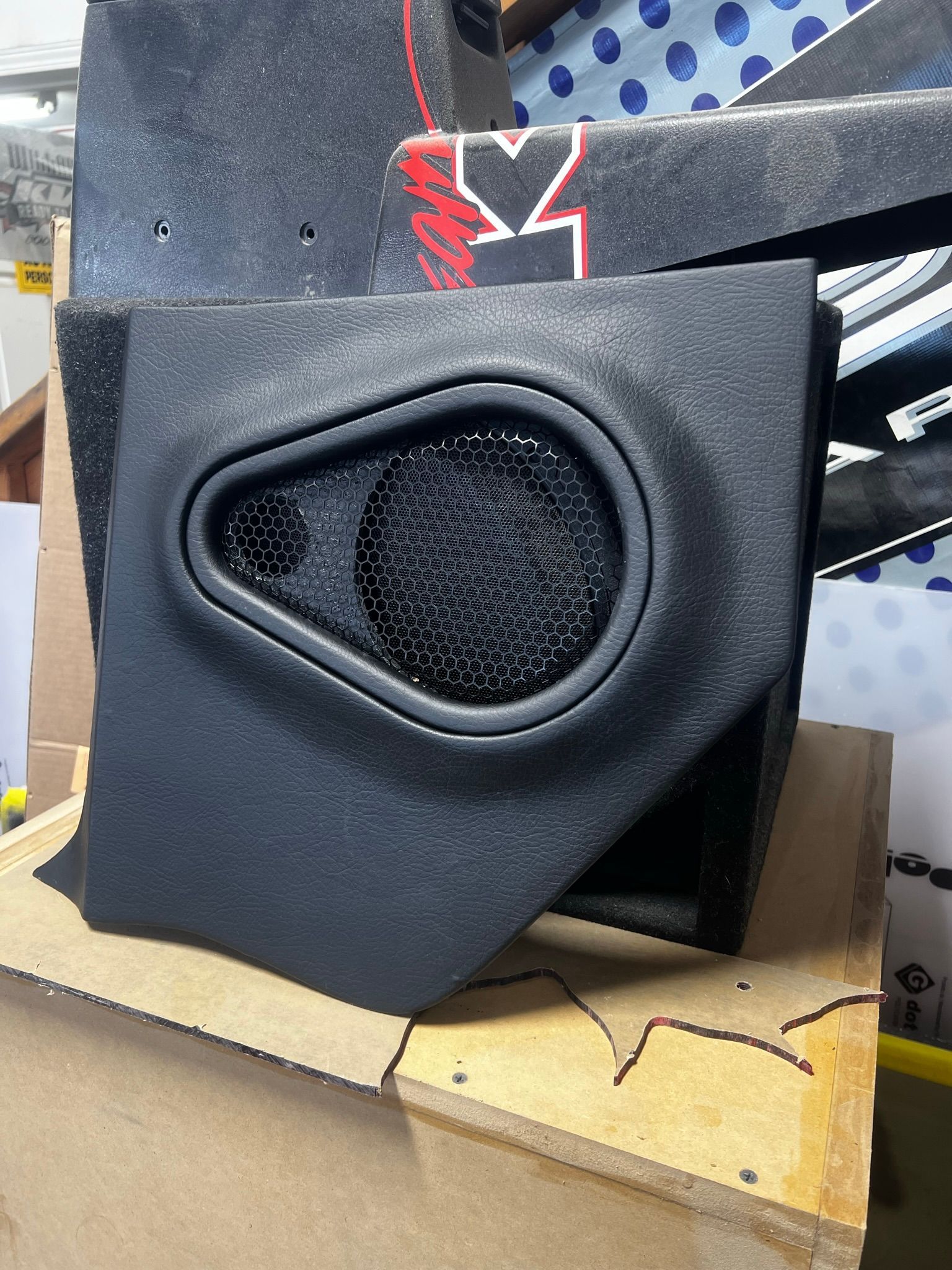 A black speaker is sitting on top of a wooden table.