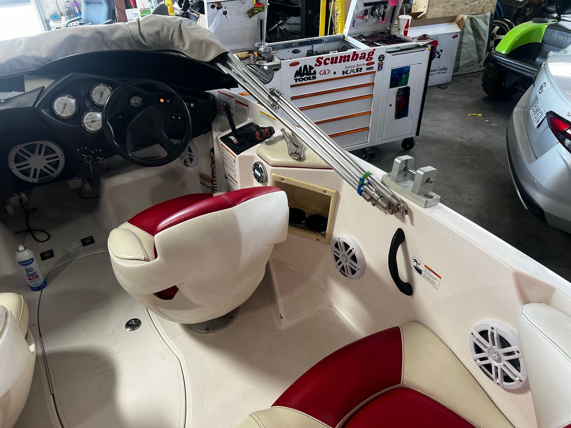 A boat is sitting in a garage next to a car.