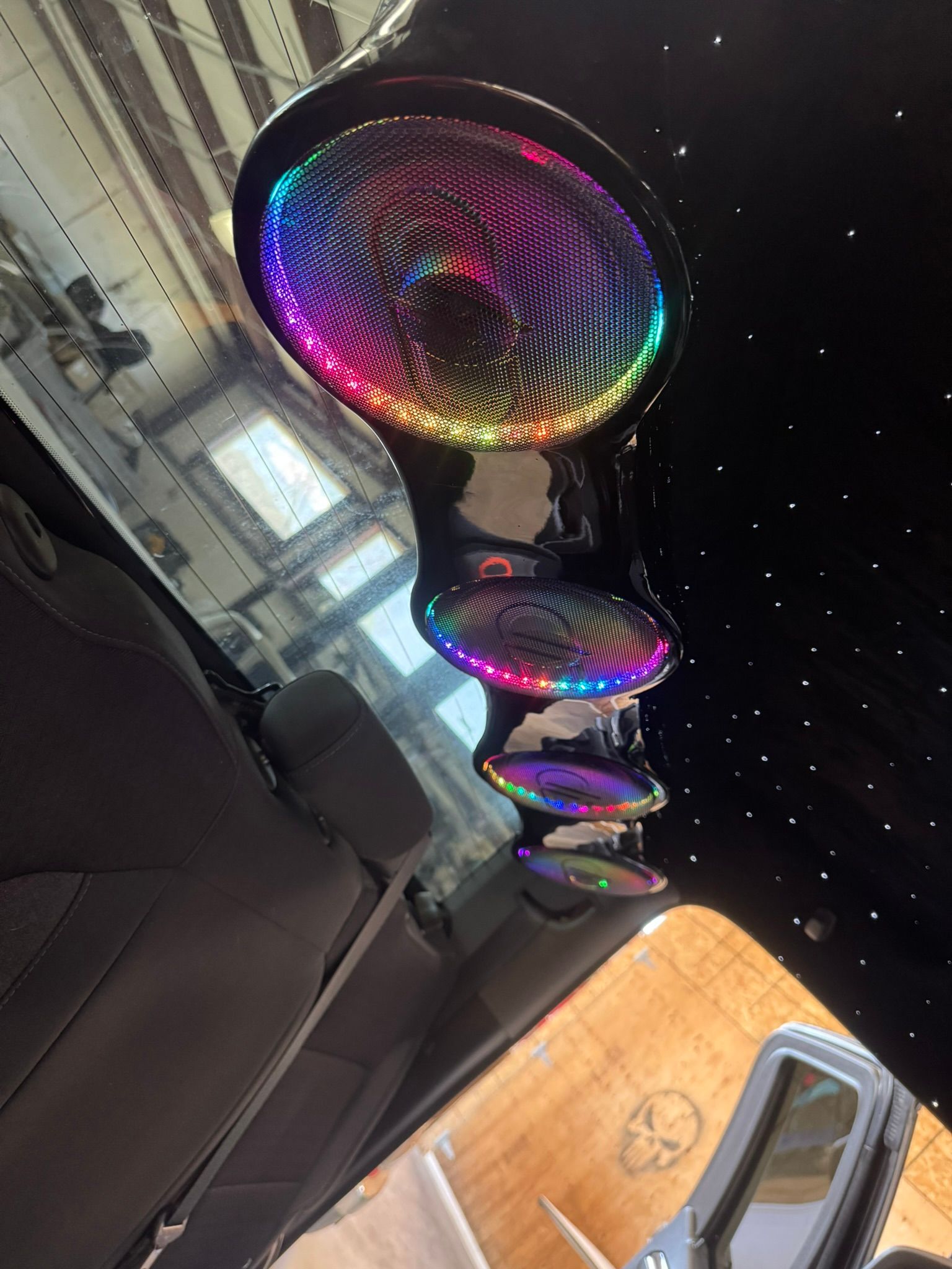 A rainbow colored object is hanging from the ceiling of a car.