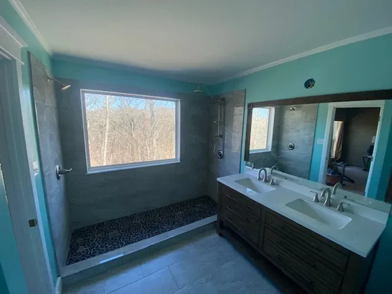 A bathroom with two sinks and a walk in shower.