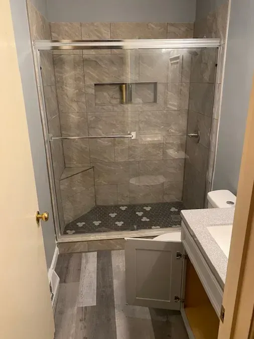 A bathroom with a sliding glass shower door and a bathtub.