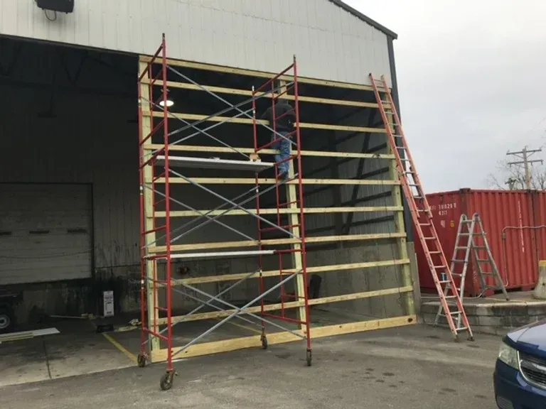 A man is standing on a scaffolding in front of a building
