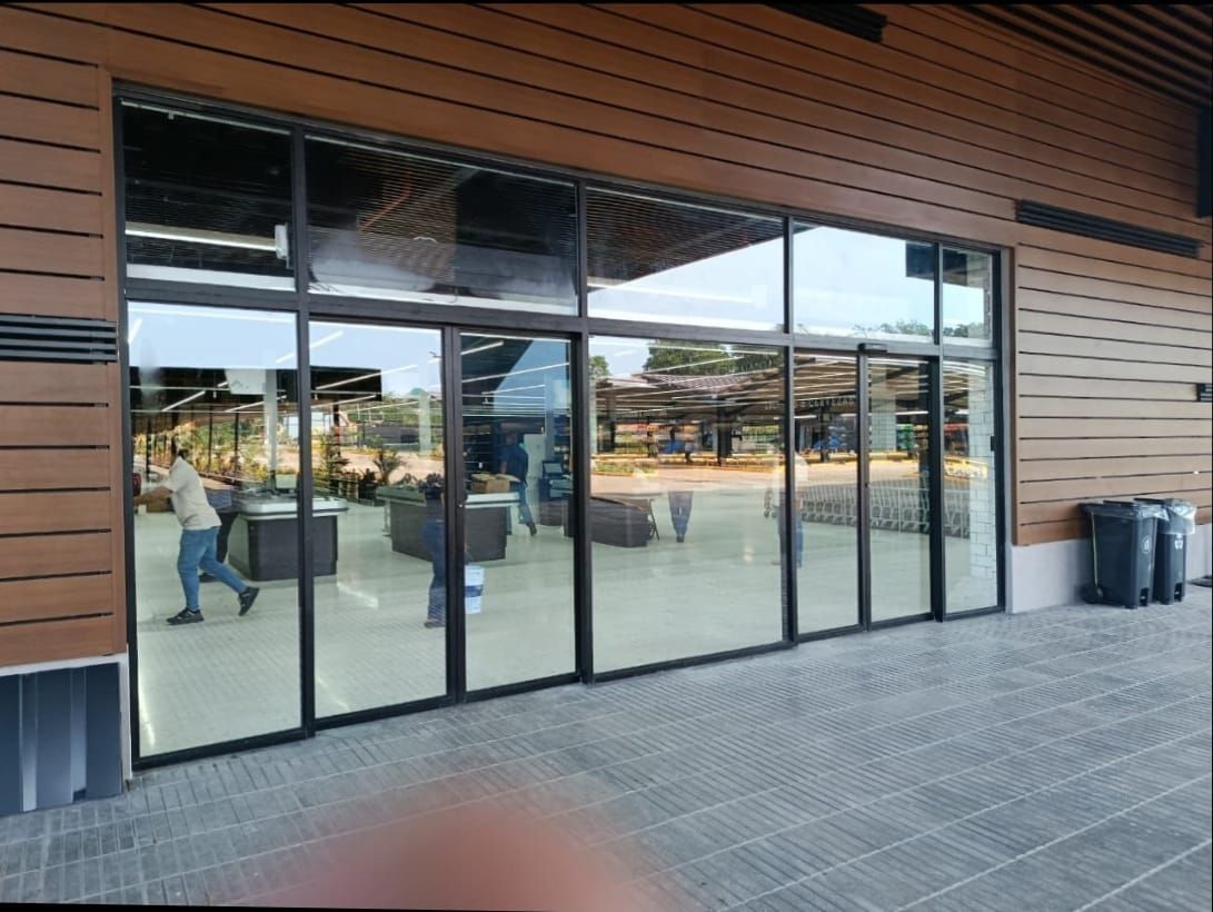 Fachada moderna con grandes puertas y ventanas de cristal que reflejan la plaza exterior.
