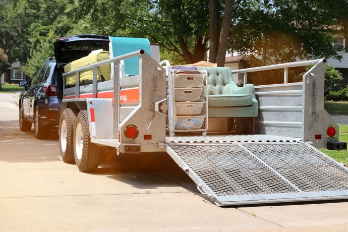 Two movers in blue uniforms loading a wrapped item into a truck