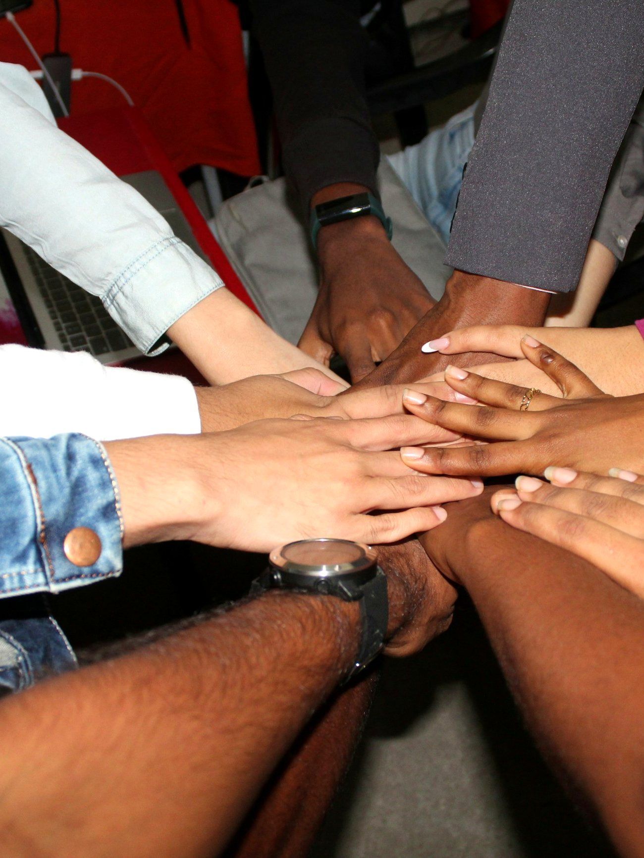 Many hands stacked together in the centre of a circle