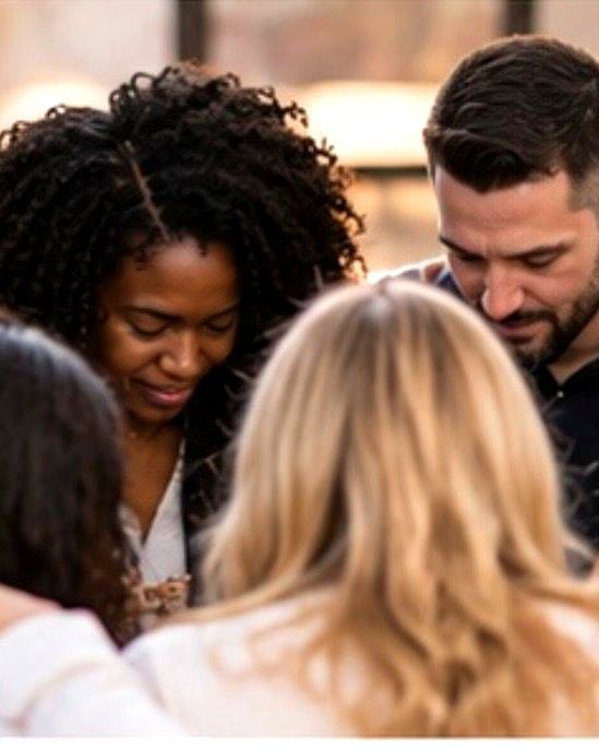 A small group praying together with arms around one another