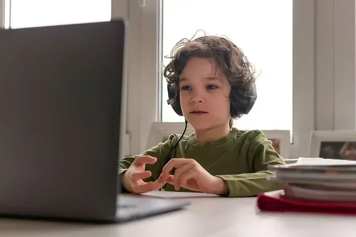 Young child with headphones on doing online class