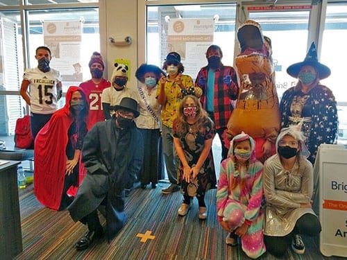 A group of people wearing masks and costumes are posing for a picture.