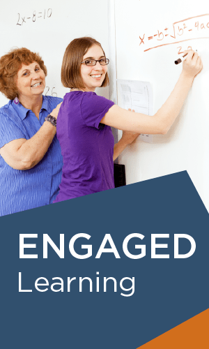 Two women are standing next to each other writing on a whiteboard.