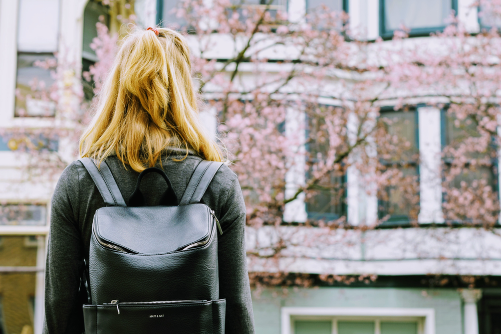 A woman with a backpack is standing in front of a building.
