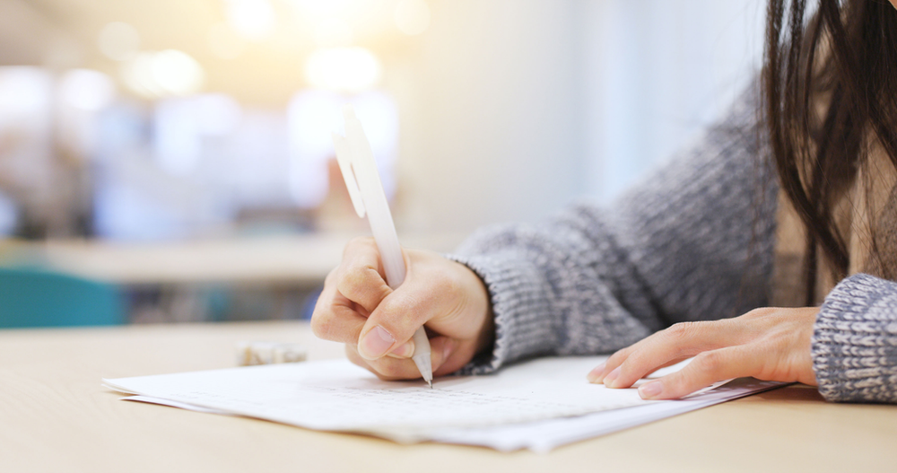 A woman is writing on a piece of paper with a pen.