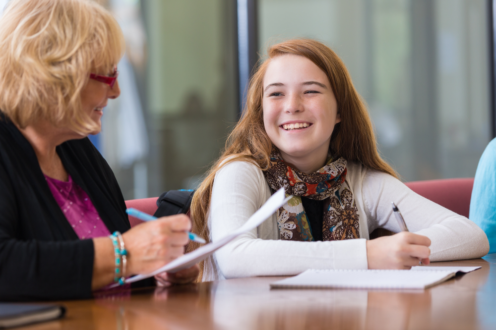 A woman is sitting at a table with a young girl.