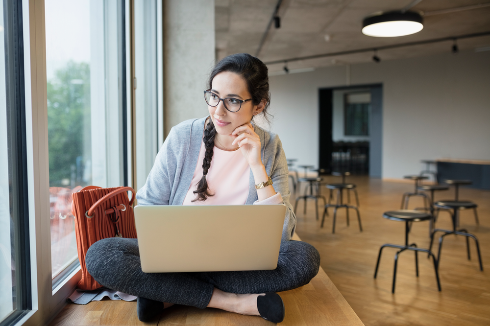 A woman is sitting on the floor using a laptop computer.