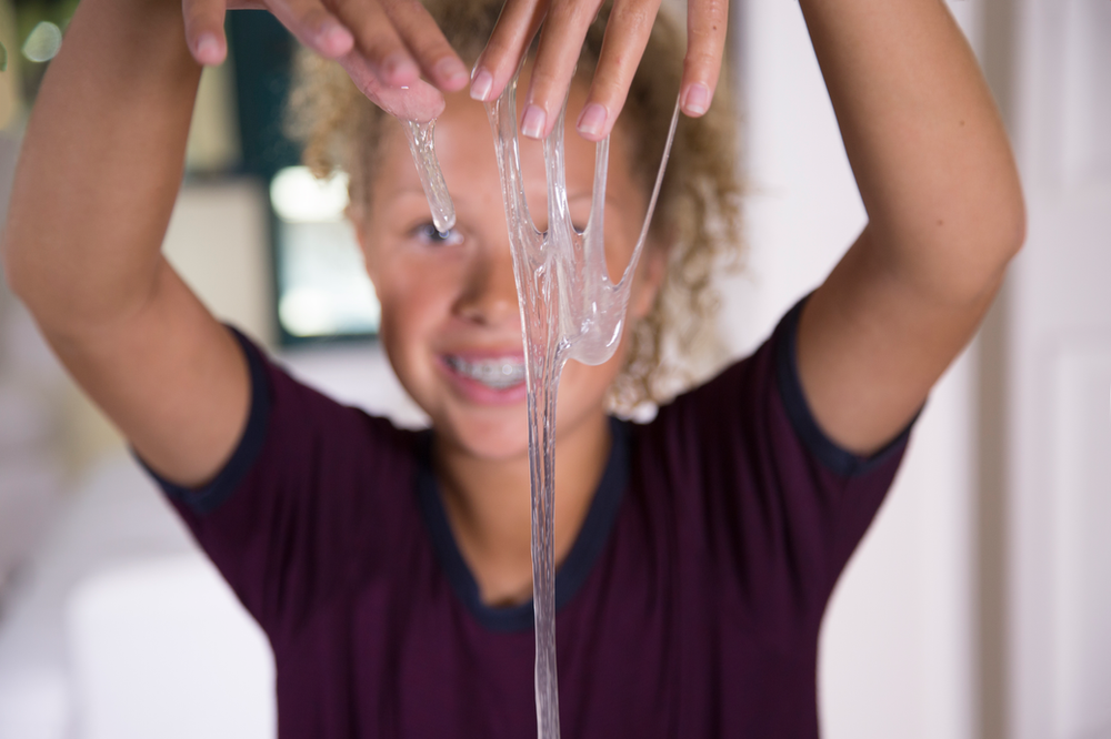 A young girl is playing with clear slime.