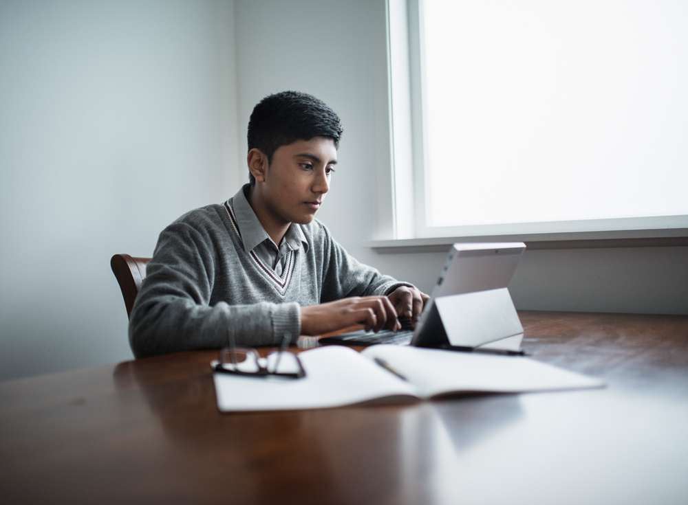 A man is sitting at a table using a laptop computer.