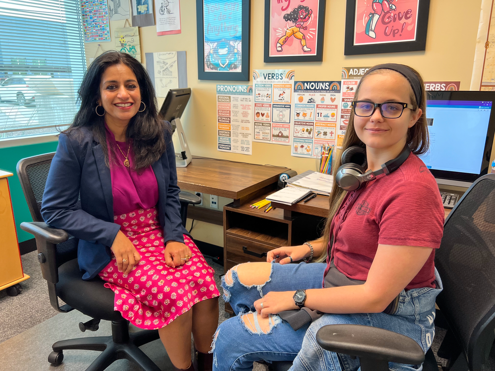 Two women are sitting in chairs in an office.
