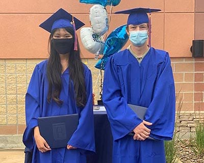 A man and a woman in graduation caps and gowns are standing next to each other.