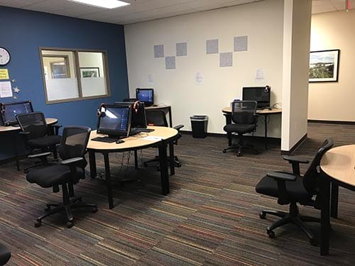 A room with tables and chairs and computers on them.