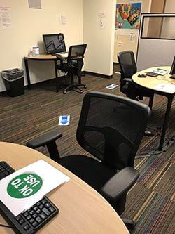 A room with a desk , chairs , computers and a keyboard.