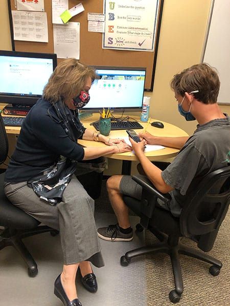 A woman is sitting at a desk with a man sitting in front of a computer.