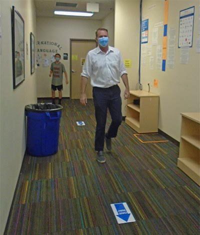 A man wearing a mask is walking down a hallway