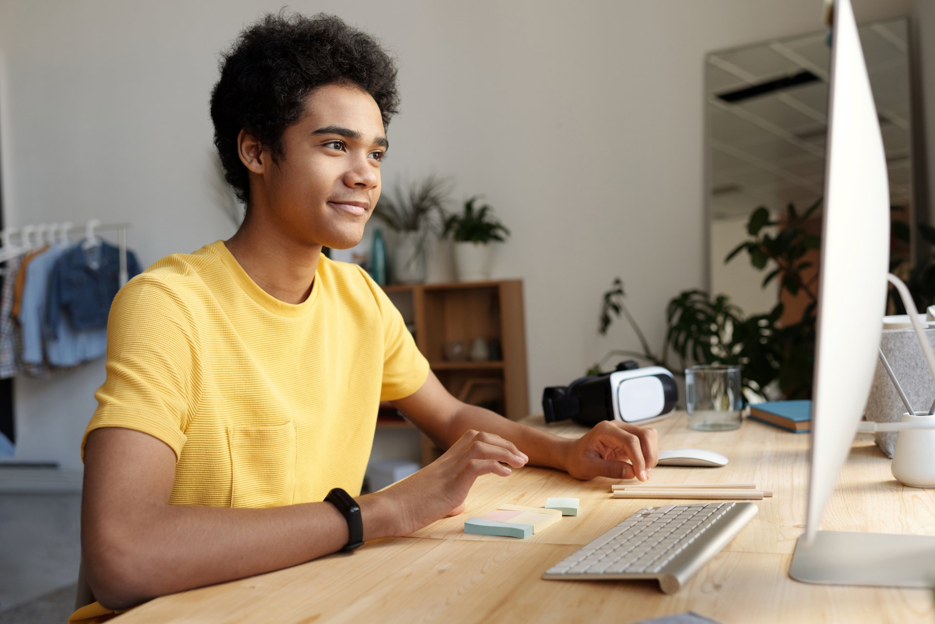 A young man is sitting at a desk in front of a computer.