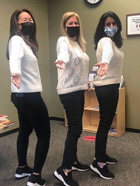 Three women wearing face masks are standing next to each other in a room.