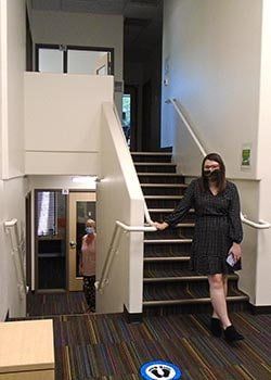 A woman wearing a mask is standing on a set of stairs.