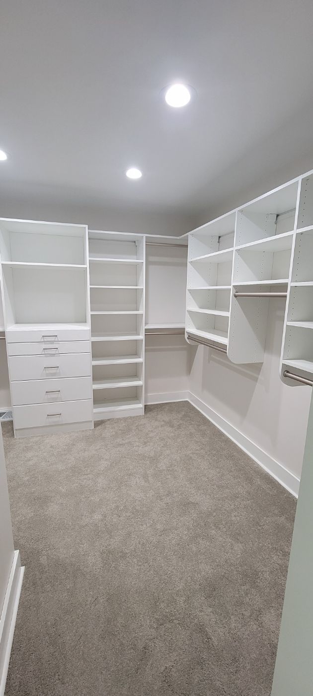 a large walk in closet with lots of shelves and drawers .